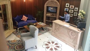 A reception area with a sofa, armchair, and a desk with a computer. - Hotel Jewel Palace (New Delhi)