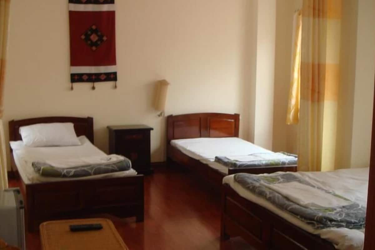 A room with two beds, a nightstand, and a wall hanging.