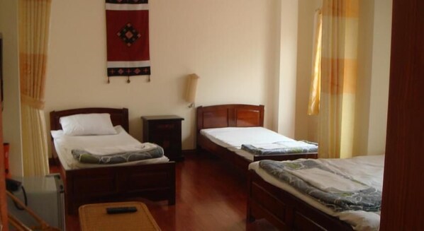 A room with two beds, a nightstand, and a wall hanging.