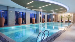 A modern indoor swimming pool with clear water, surrounded by large windows and potted plants. - Wanda Realm Changzhou (Changzhou)