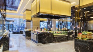 A modern hotel lobby with a marble reception desk, a buffet area, and a large glass window offering a view of the city. - Wanda Realm Changzhou (Changzhou)