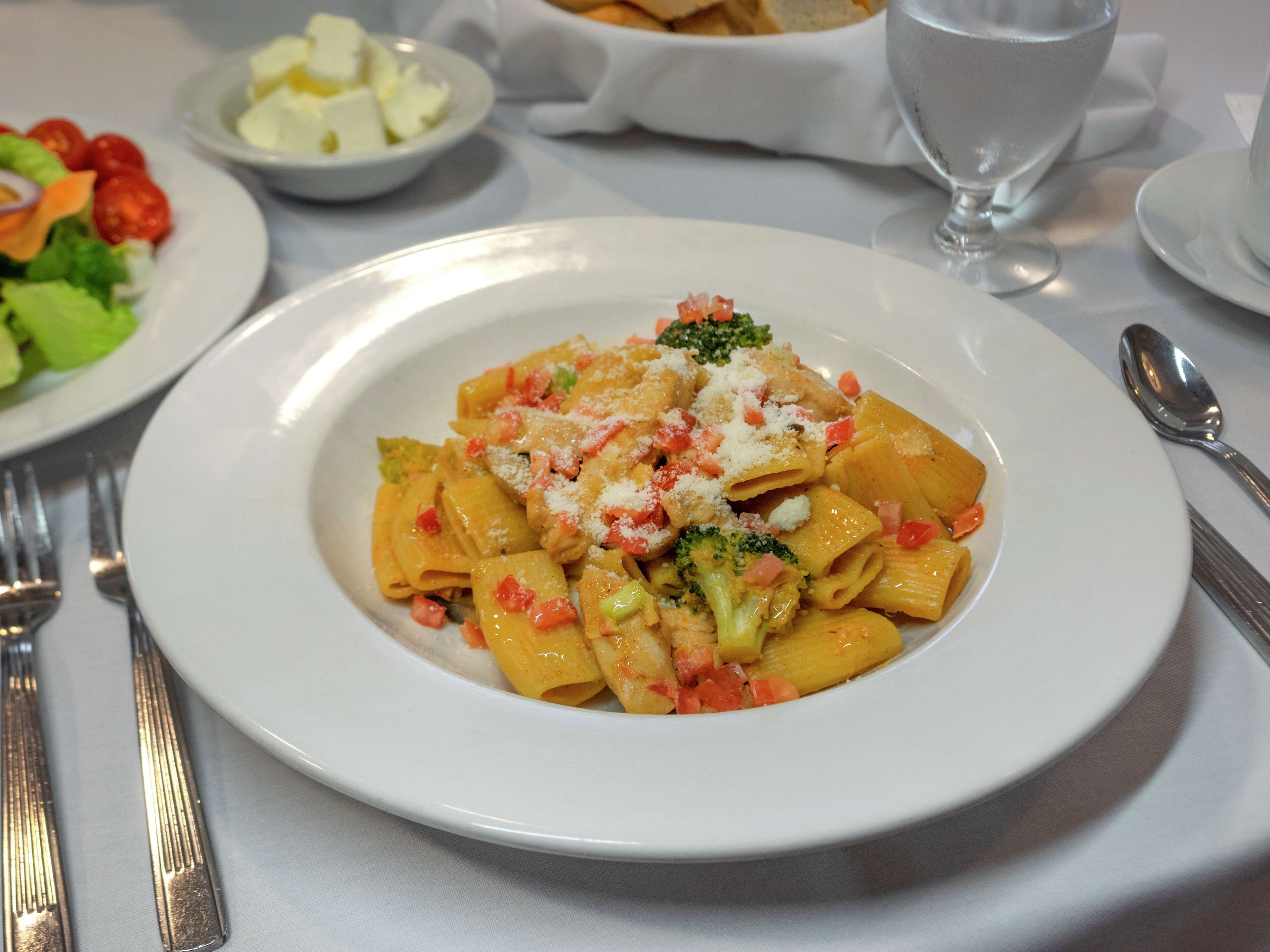 Un plato de pasta con brócoli y queso sobre un plato blanco.