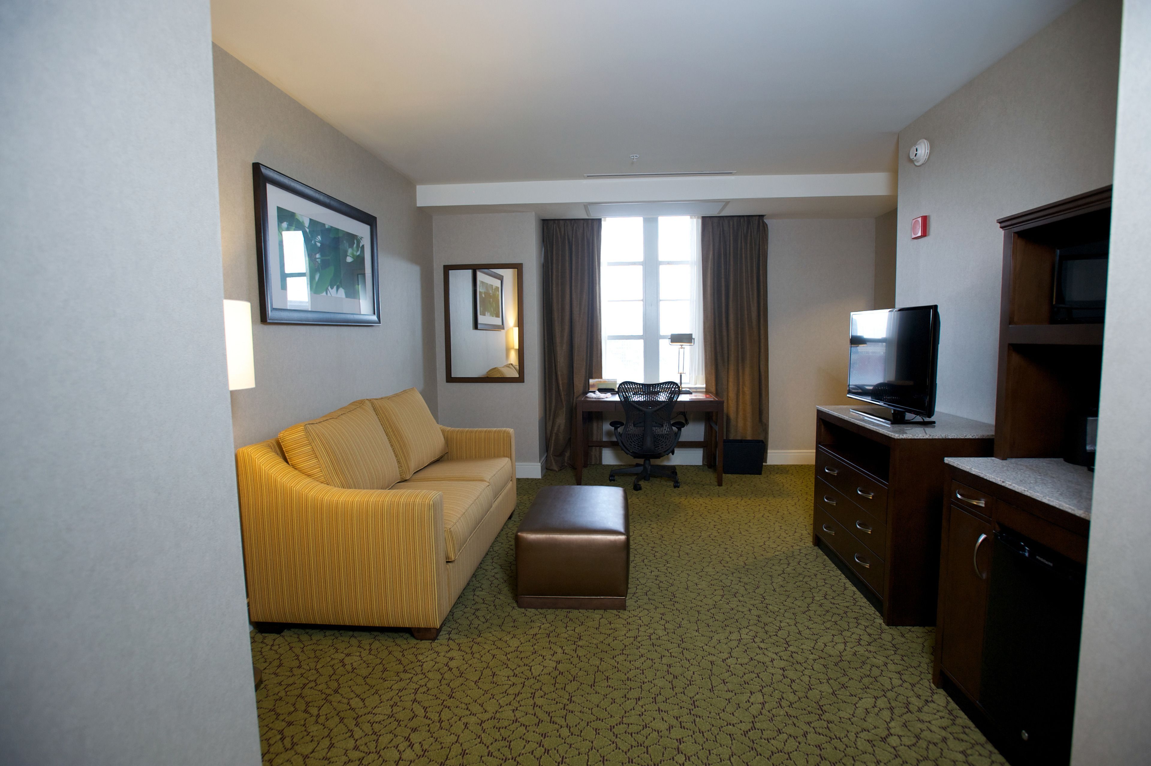 A hotel room with a sofa, a small table, a television, and a cabinet.