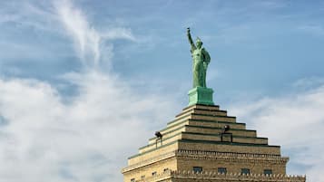 La Estatua de la Libertad sobre un edificio, con cielo despejado al fondo.