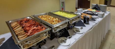 A buffet table with various food options, including meats, potatoes, and other dishes, in a hotel setting.