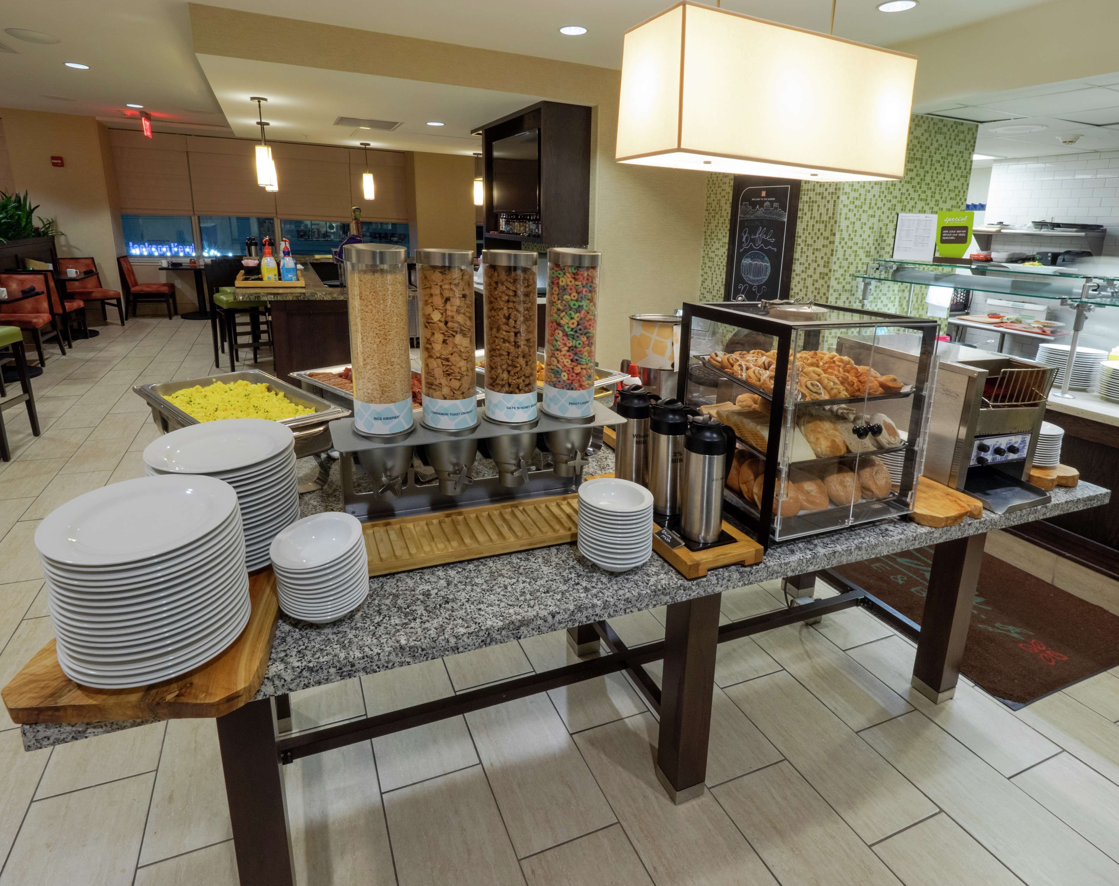 Un buffet avec différents distributeurs de nourriture, des assiettes et un coin café.