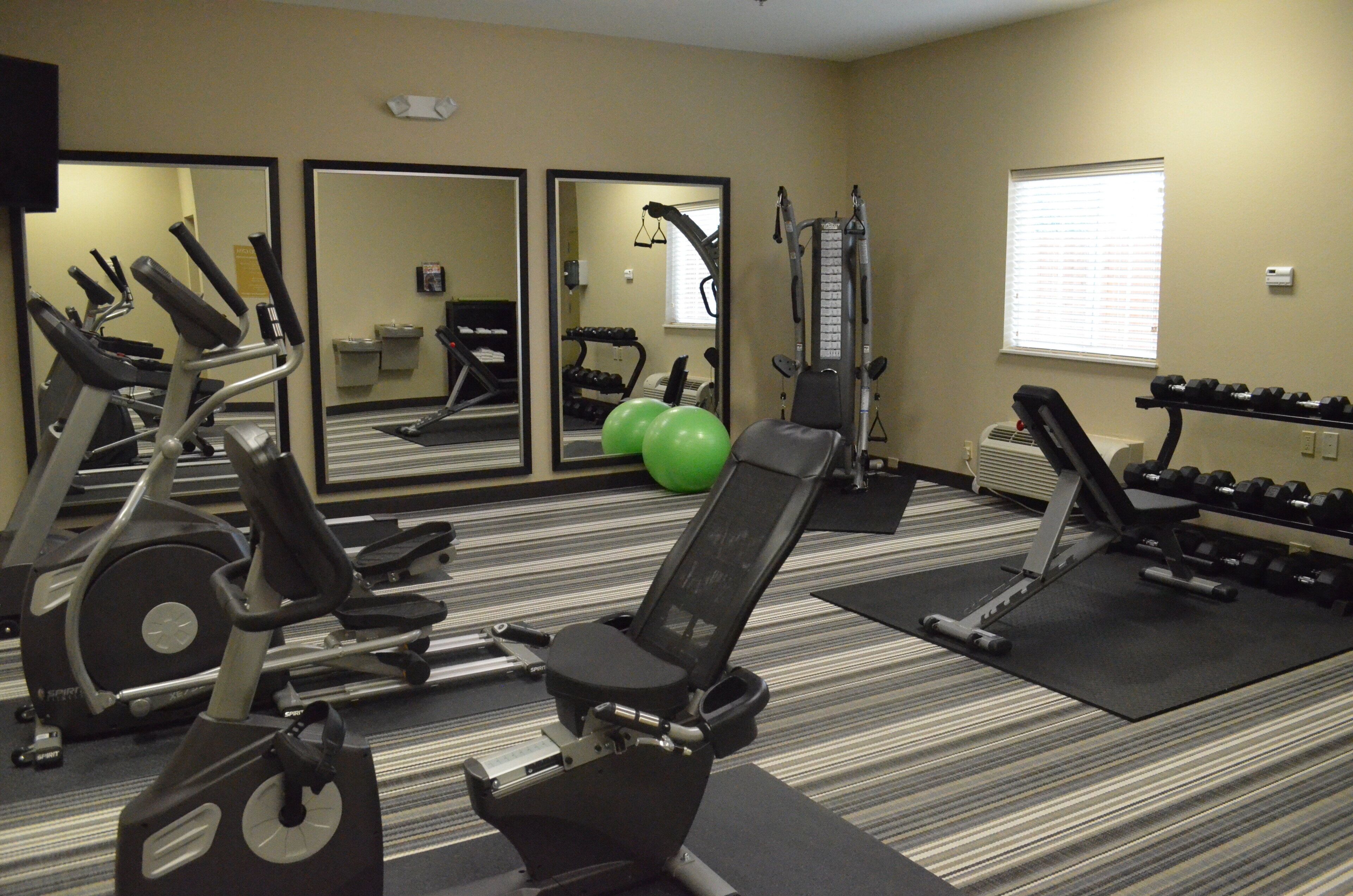 A gym with exercise equipment, mirrors, and a window.