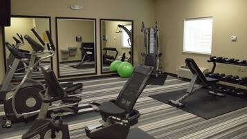 A gym with exercise equipment, mirrors, and a window.