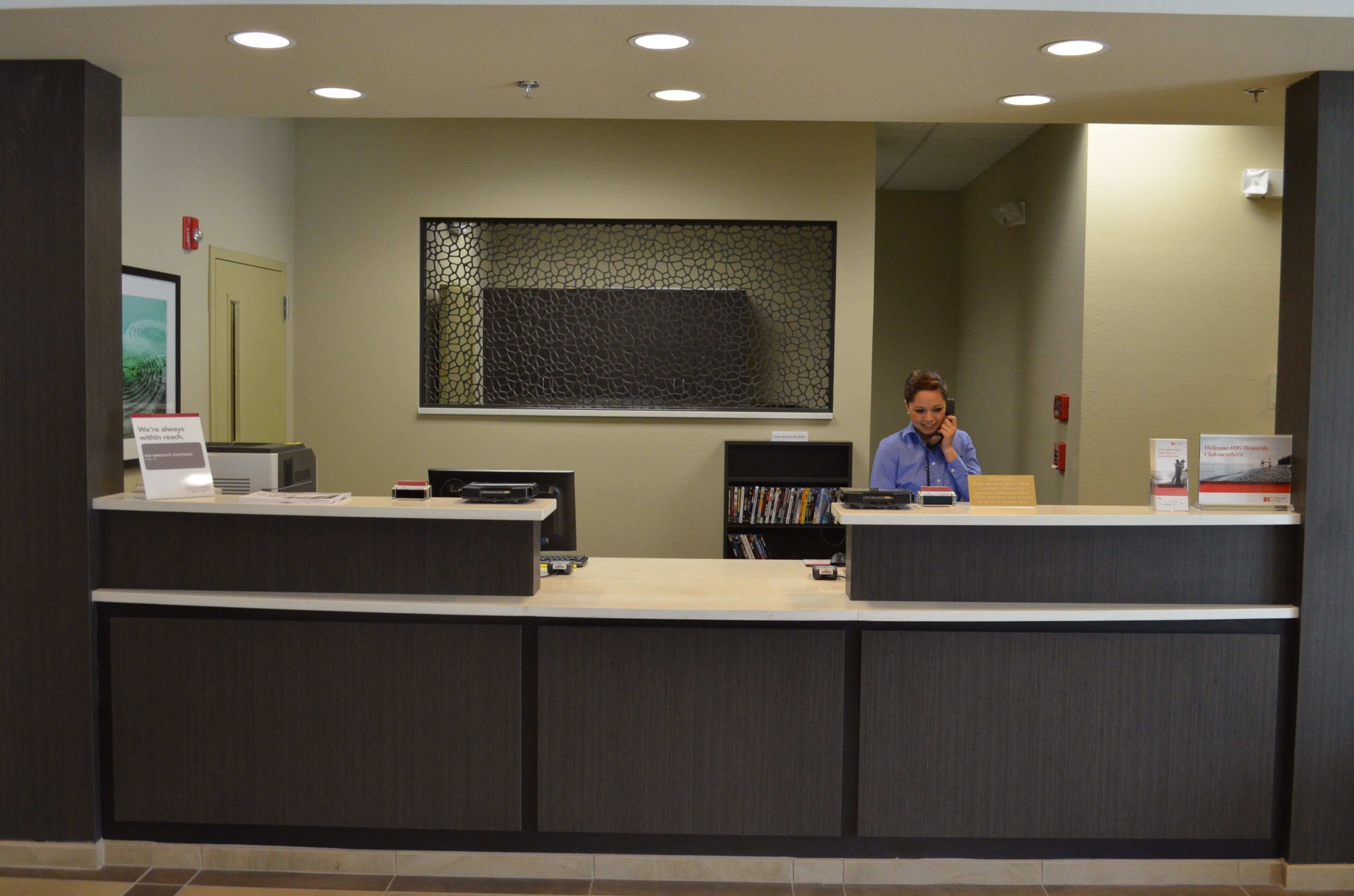 A reception desk with a computer, a telephone, and a bookshelf with magazines.