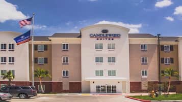 Un hotel de varios pisos con un llamativo letrero 'CANDLEWOOD SUITES', que presenta una fachada simétrica con ventanas distribuidas uniformemente y una entrada central.