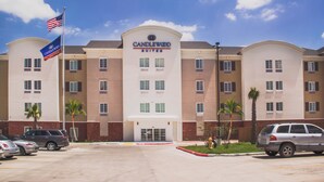 A hotel with a prominent 'Candlewood Suites' sign, multiple windows, and a parking lot with cars. - Candlewood Suites Harlingen by IHG (Harlingen)