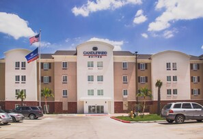 Een hotel met een goed zichtbaar 'Candlewood Suites' bord, meerdere ramen en een parkeerplaats met auto's.