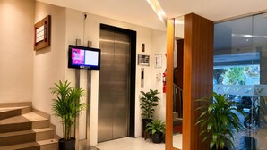 An elevator with a digital display, a staircase, and potted plants. - Vio Veteran (Bandung)
