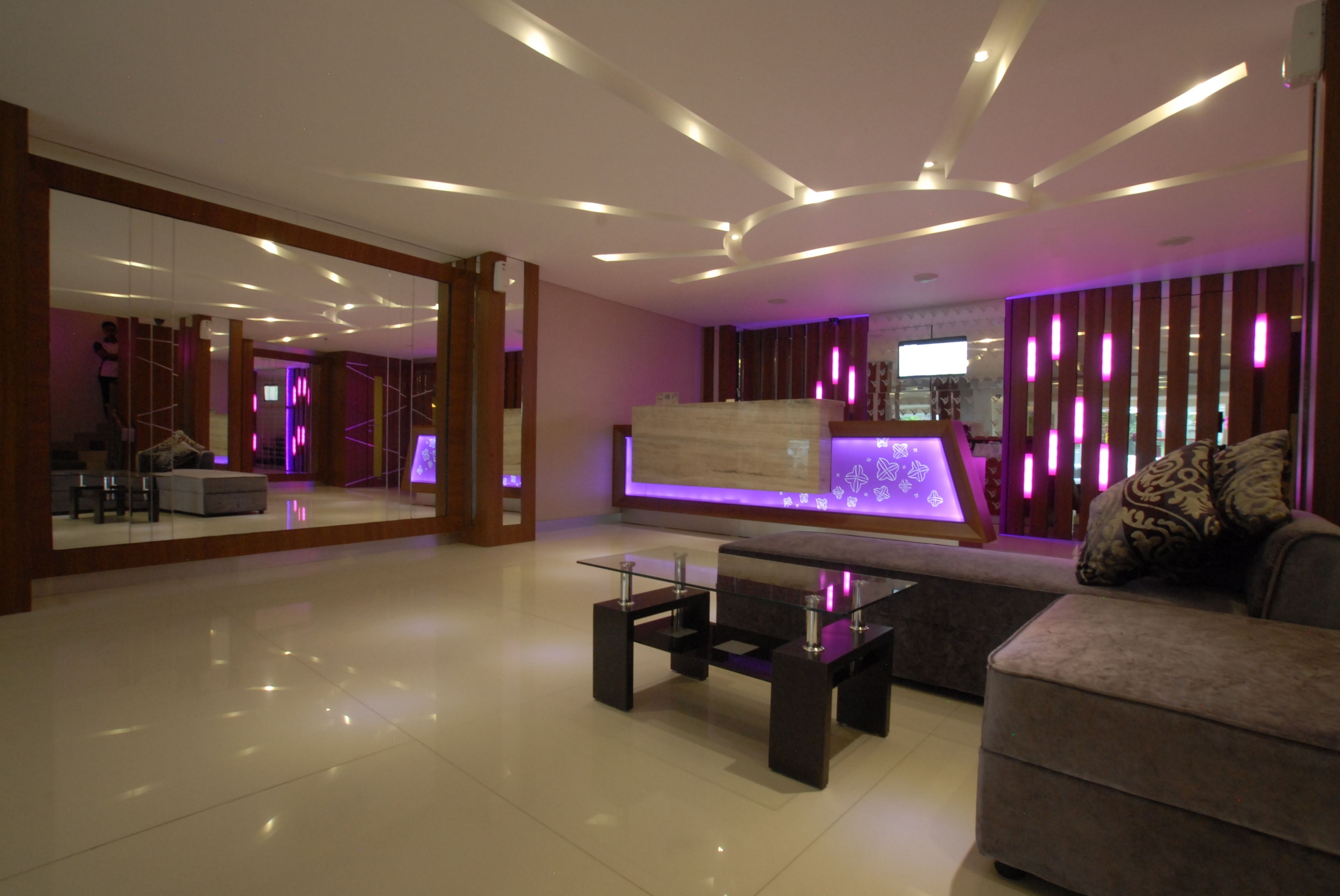 A modern living room with a glass coffee table, a sofa, and a television.