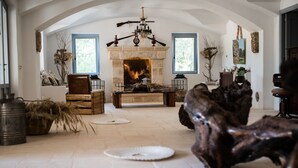 A spacious living room with a stone fireplace, wooden furniture, and a chandelier. - Masseria Lama di Coccaro (Fasano)