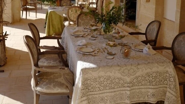 An outdoor dining area with a table set for four, surrounded by chairs. - Masseria Lama di Coccaro (Fasano)
