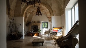 A spacious room with stone walls, a fireplace, and a large window. - Masseria Lama di Coccaro (Fasano)