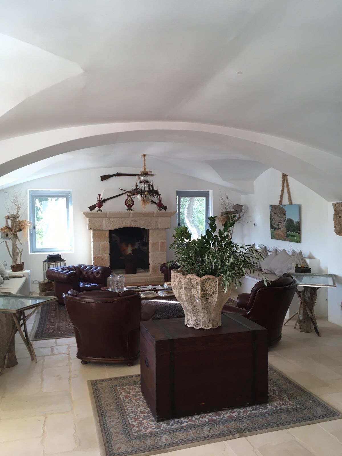 A spacious living room with a fireplace, leather sofas, a coffee table, and a large potted plant.