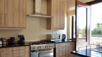 A modern kitchen with wooden cabinets, a gas stove, a microwave, and a coffee maker.