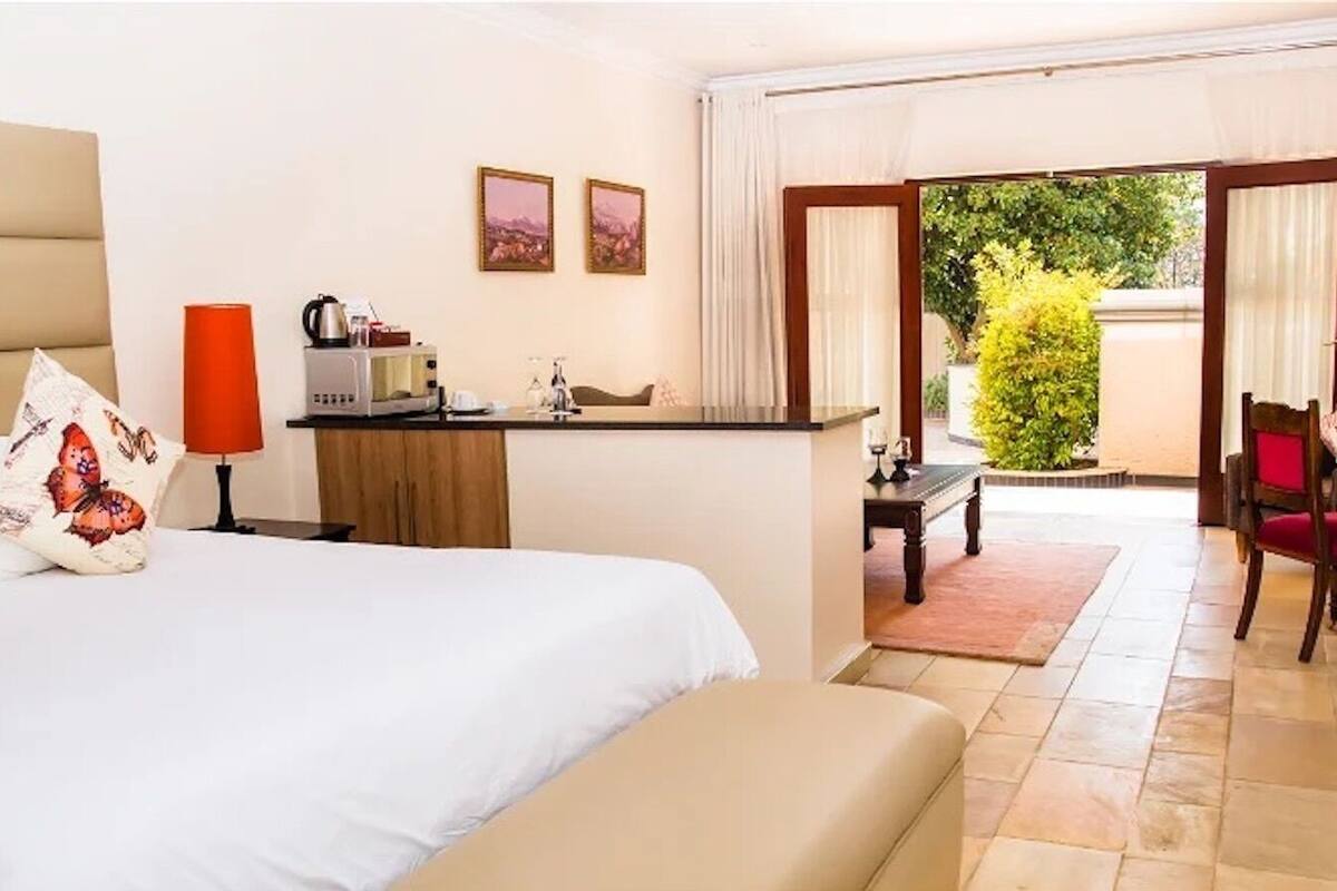 Quarto de hotel com cama, escrivaninha, cadeira e vista para o exterior.