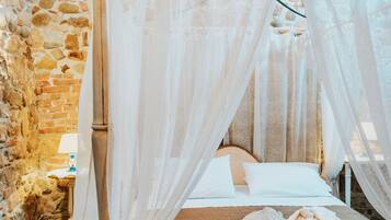 Un dormitorio con paredes de piedra, una cama con dosel, una mesita de noche y una lámpara.