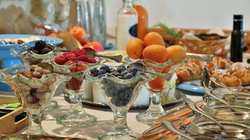 A buffet with various food items including fruits, pastries, and beverages.