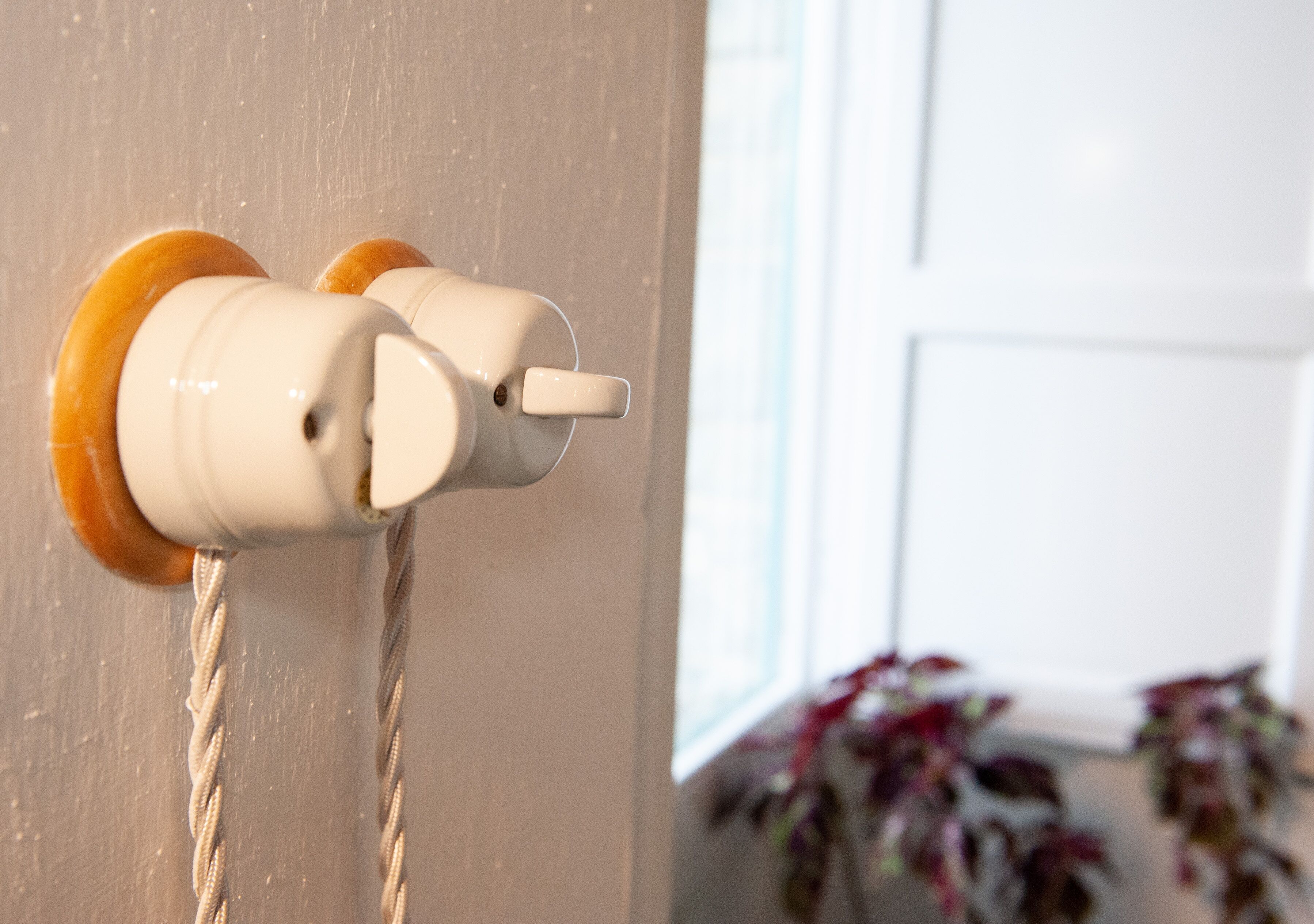Een witte muur met een deurklink en een touw dat eraan hangt.