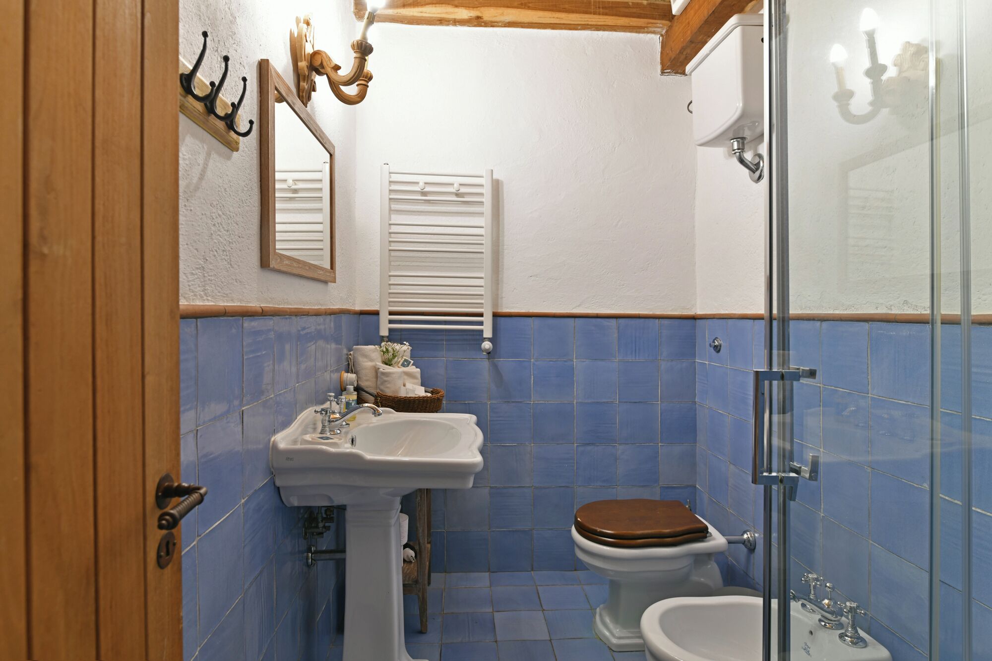 A bathroom with a sink, toilet, bidet, and a glass shower enclosure.