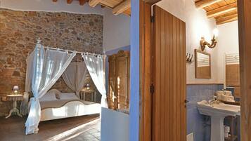 Une chambre avec un mur en pierre, un lit à baldaquin et un plafond en bois.