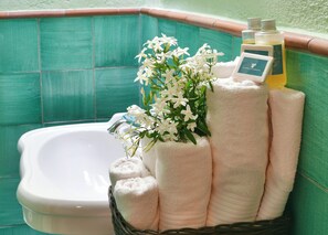 A bathroom with a bathtub, a basket of towels, a vase with white flowers, and toiletries. - Terre di Himera (Termini Imerese)