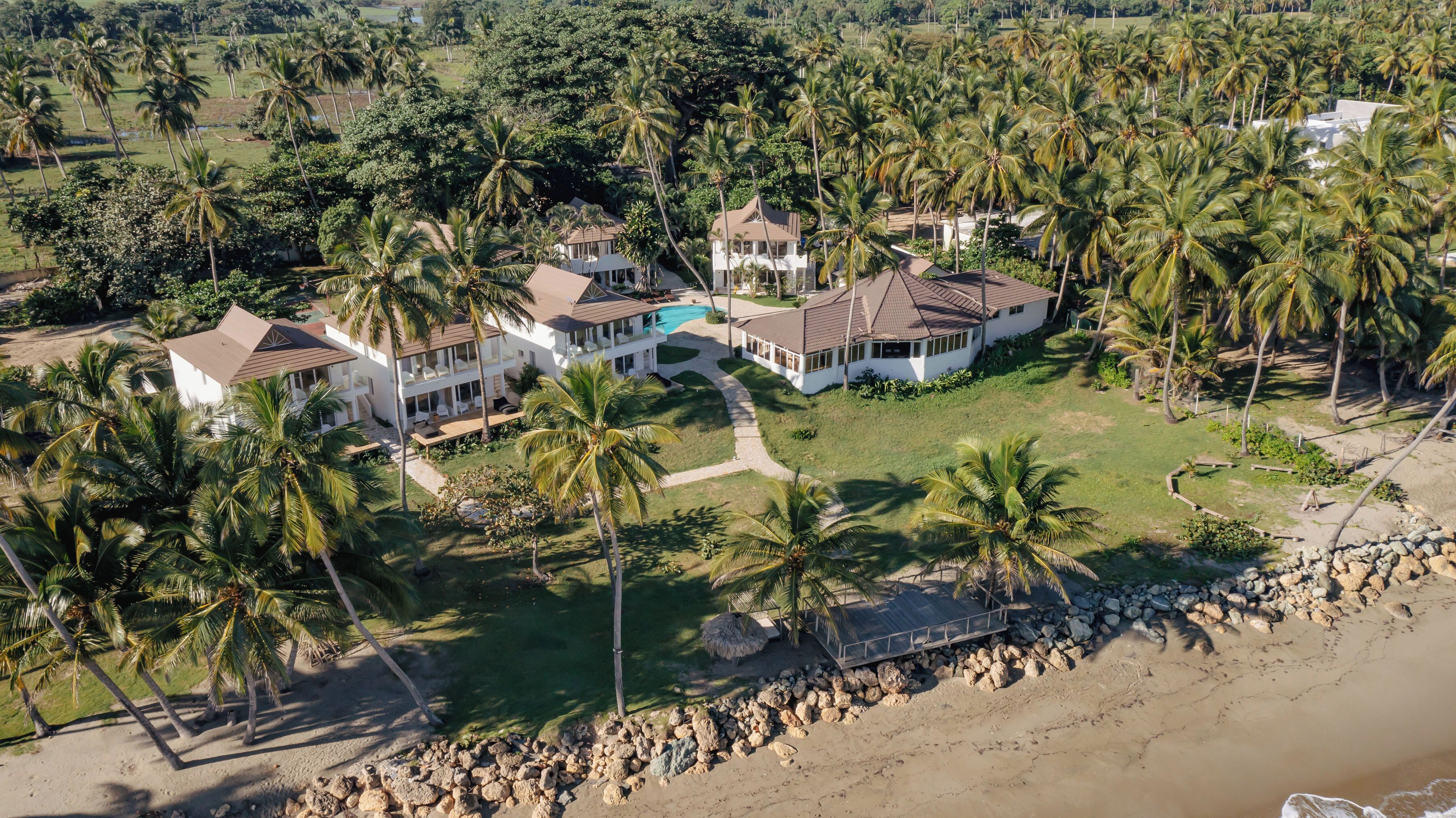 Un gran resort de varios pisos con varias construcciones, piscina y zona de playa con costa rocosa.