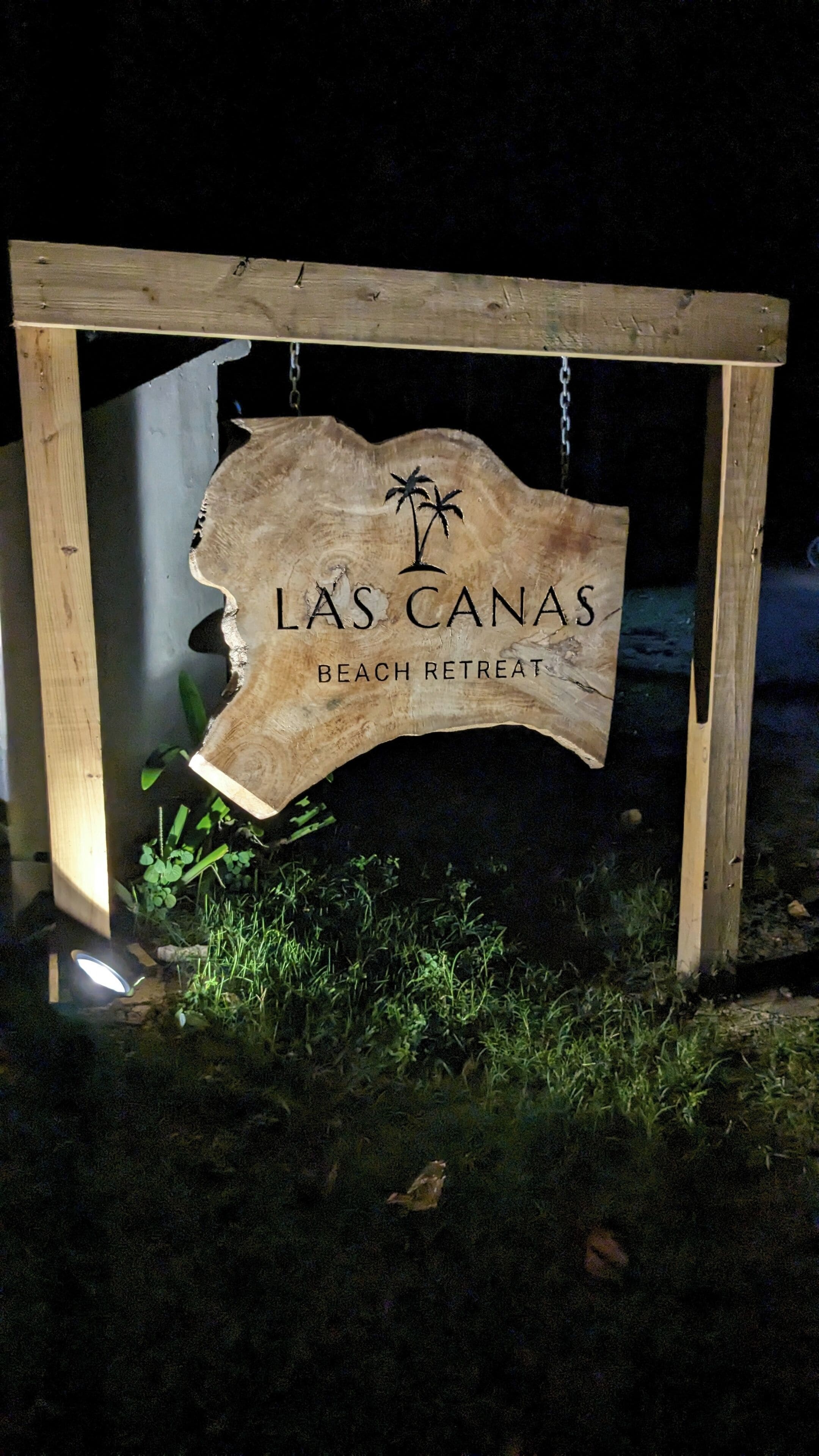 Ein hölzernes Schild mit dem Schriftzug "L's Canas Beach Retreat" in einem Holzrahmen befestigt.