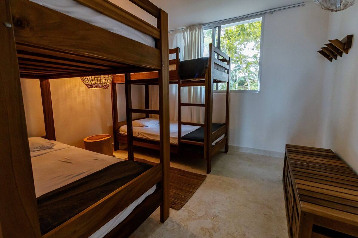 A bunk bed room with a window, a bedside table, and a small rug.