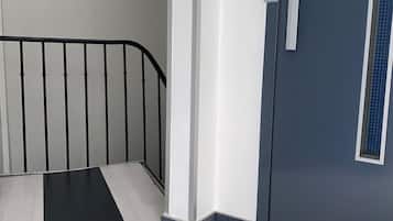 Un intérieur moderne avec un escalier, une porte dotée d’une fenêtre et un mur à texture.
