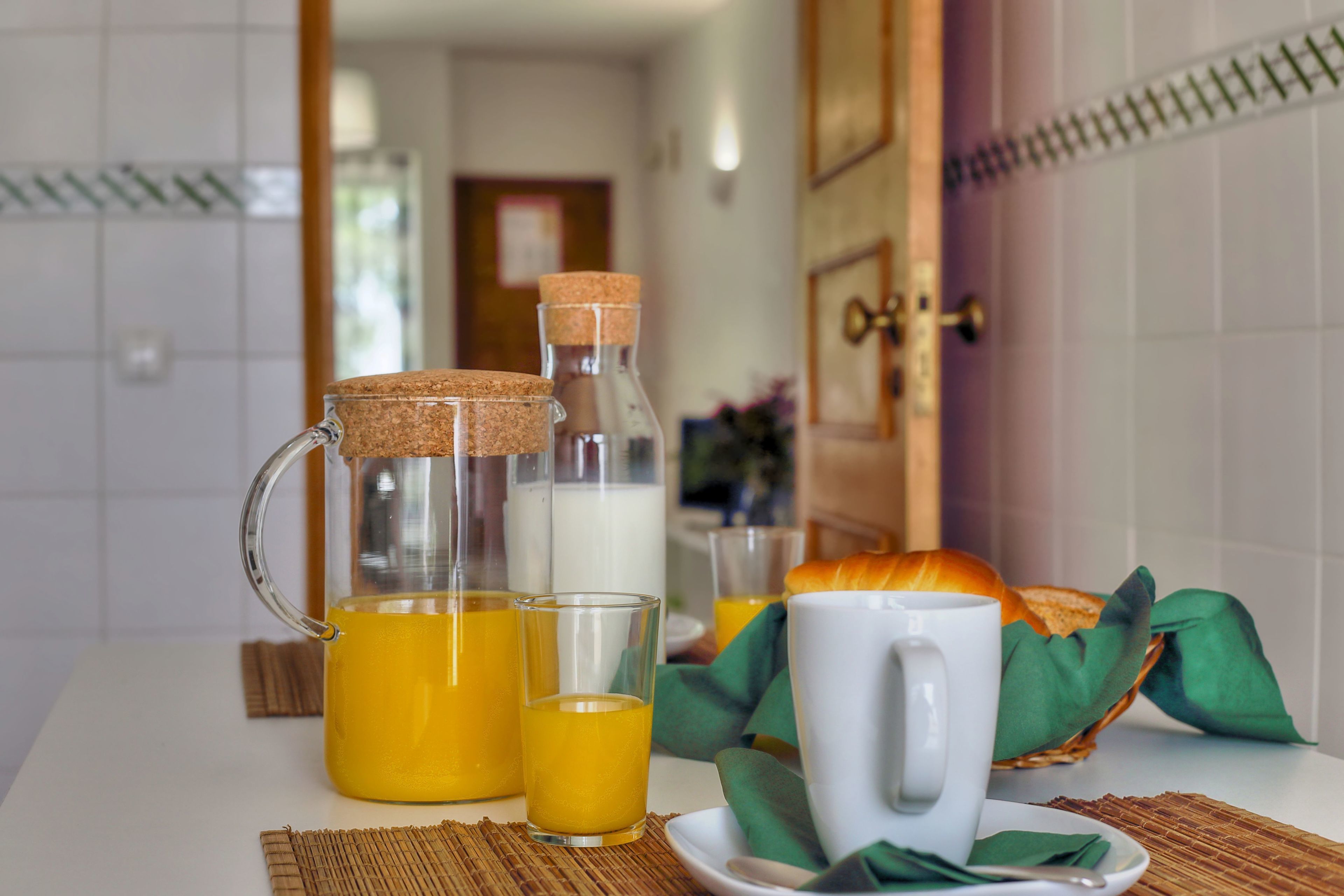 Une table mise pour le petit-déjeuner, avec une carafe, des verres, une tasse et un croissant.