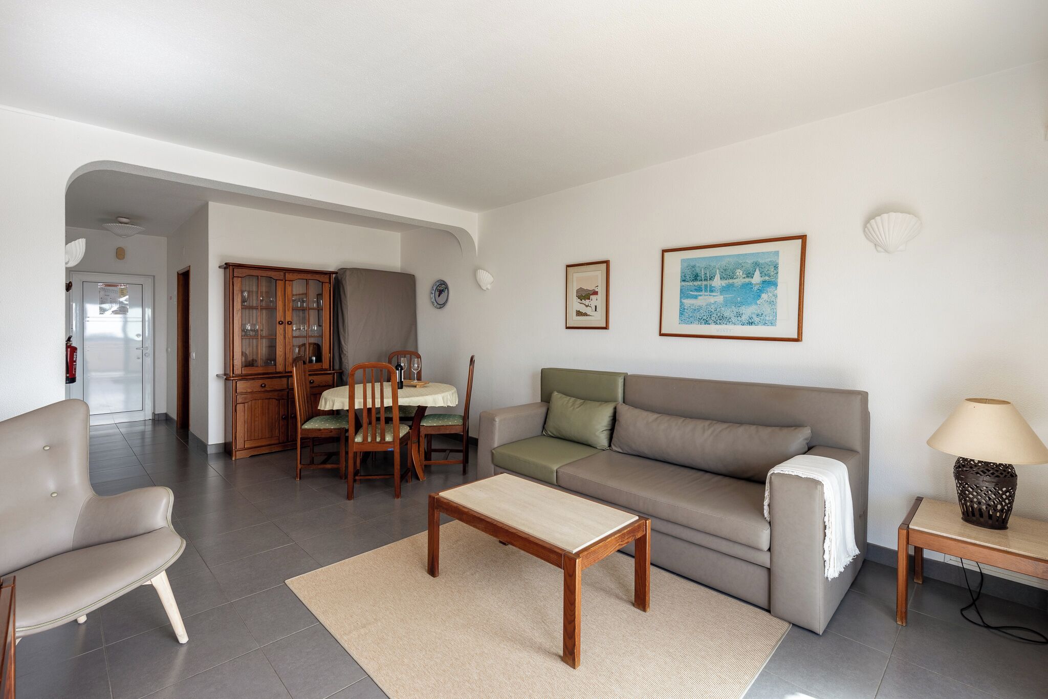 En stue med sofa, sofabord, spisebord med stole og et skab.