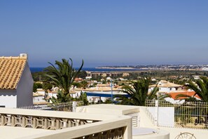 A coastal town with buildings, palm trees, and a clear blue sky.