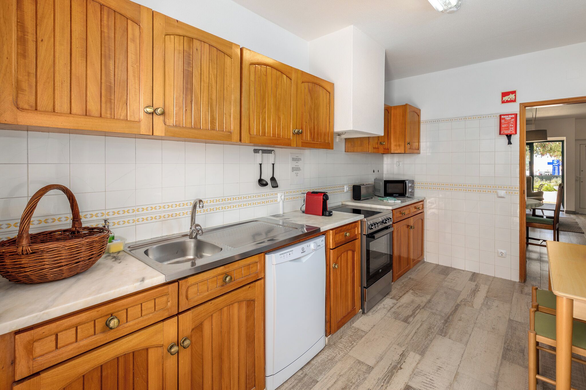 Une cuisine avec des meubles de rangement en bois, un lave-vaisselle, un four à micro-ondes et un évier.