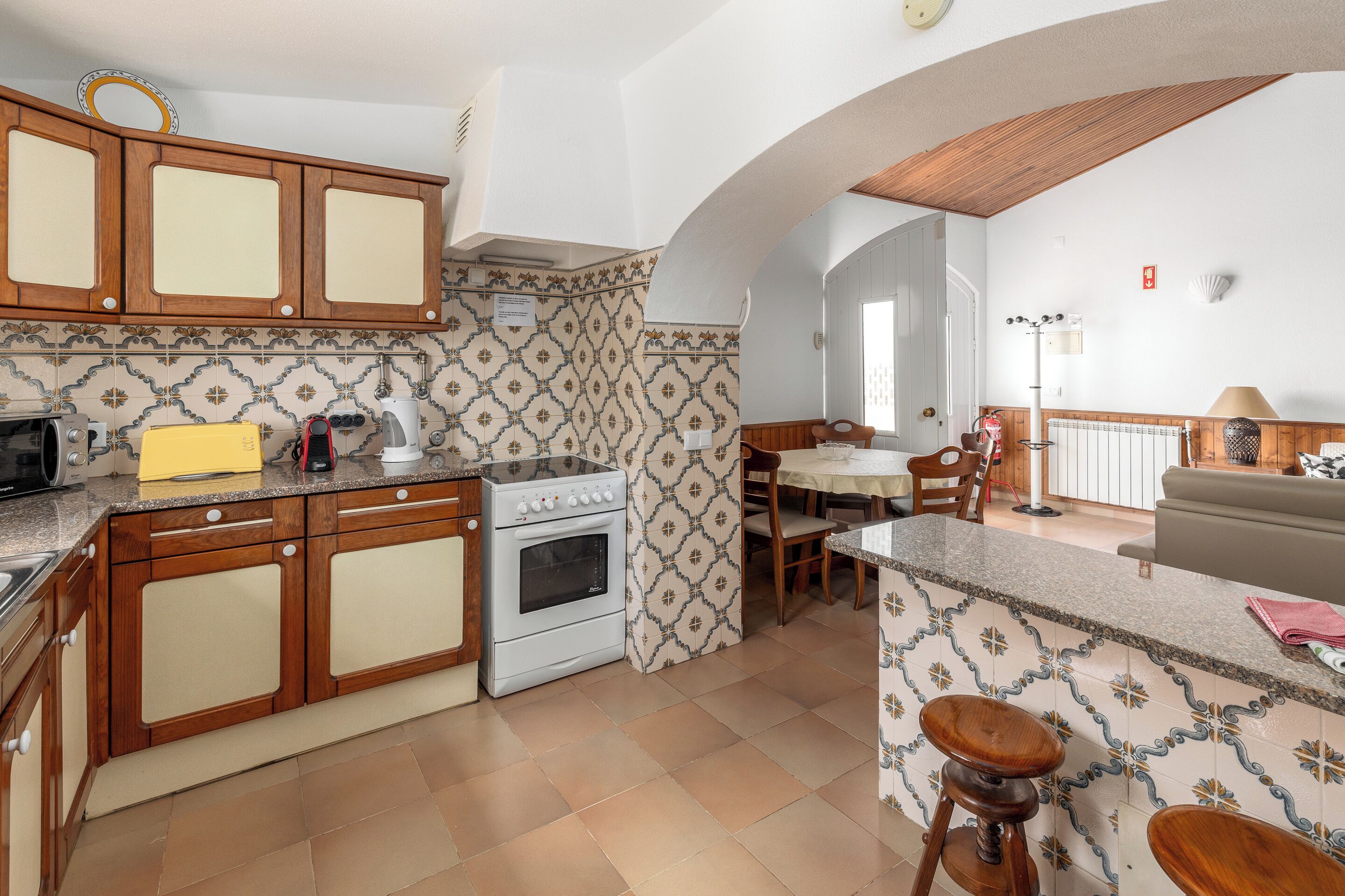 Uma cozinha com armários de madeira, um fogão e uma área de refeições com mesa e cadeiras.