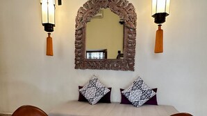 A room with a sofa, two leather armchairs, a coffee table, a decorative mirror, and wall-mounted lights. - Le Riad Jardin Des Rêves By La Siredrah (Marrakech)