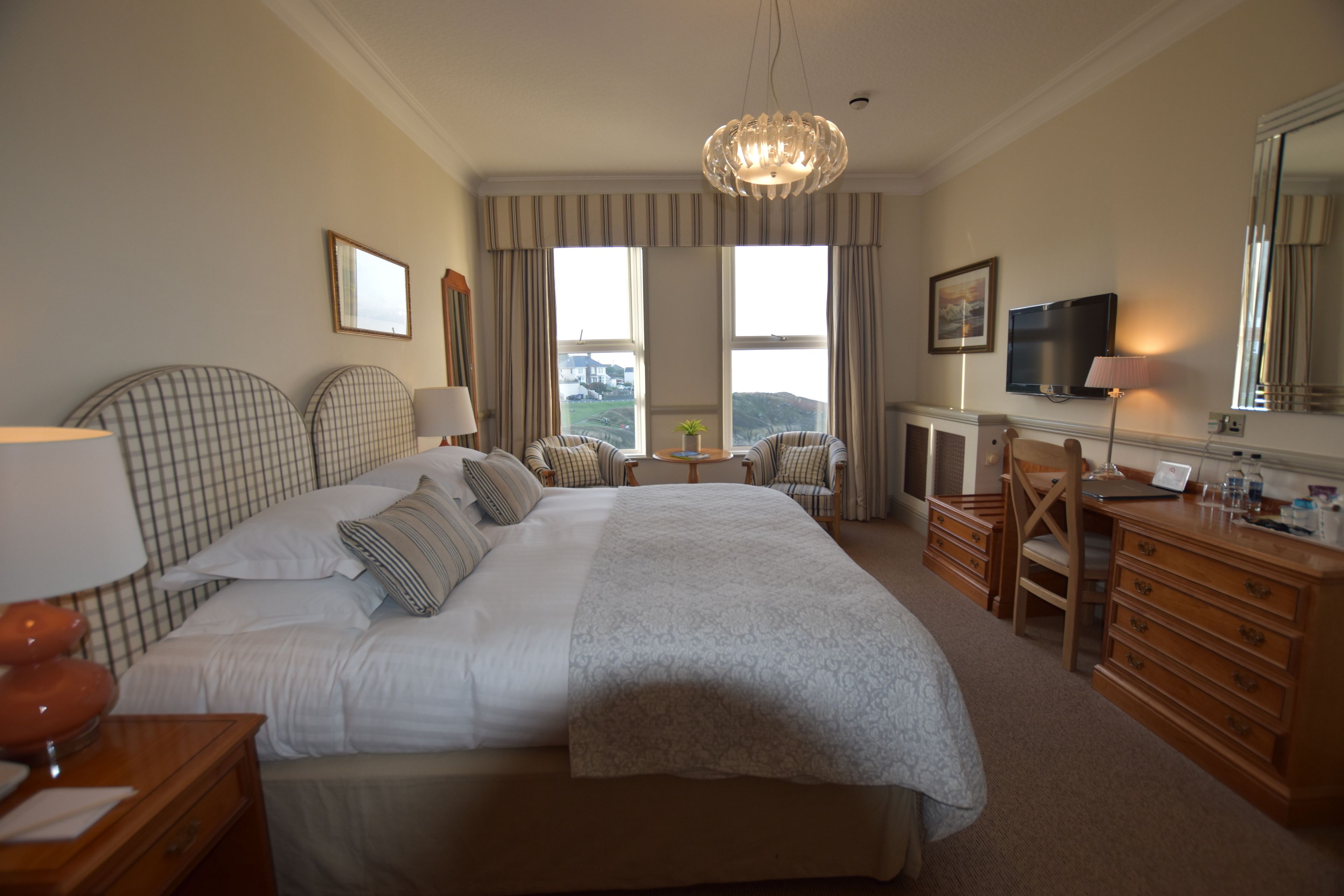Une chambre d’hôtel avec un grand lit, un bureau, une chaise, une télévision et une vue sur l’extérieur.