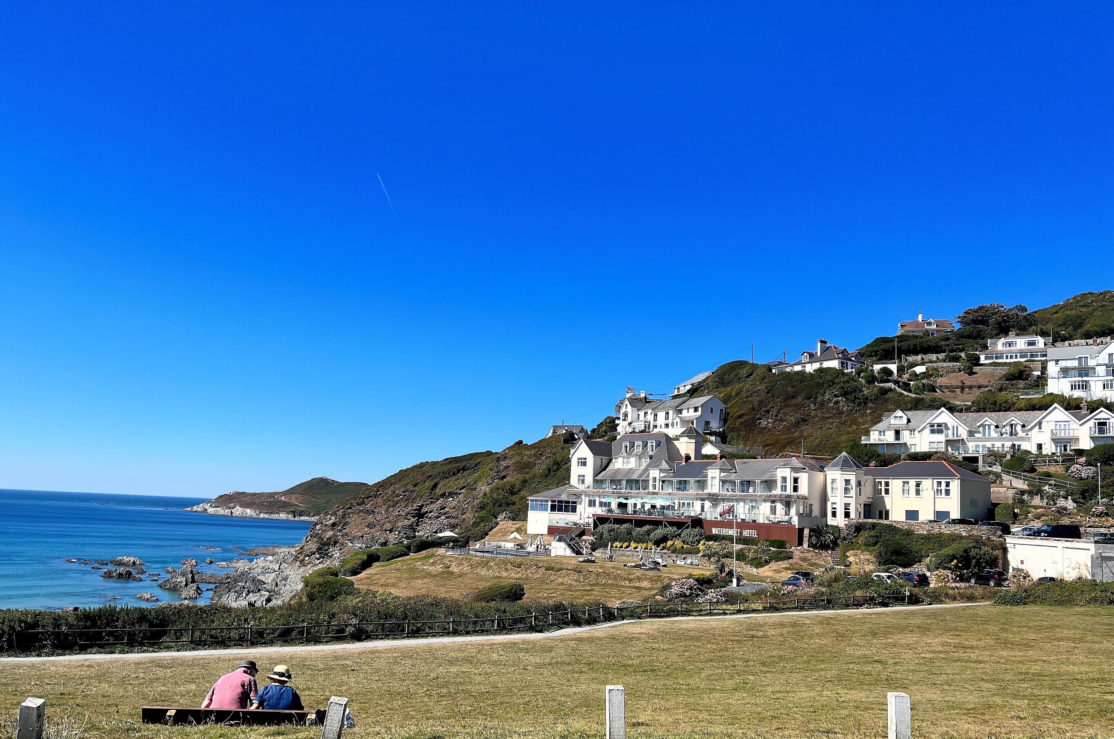A coastal residential area with houses on a hillside overlooking the sea.