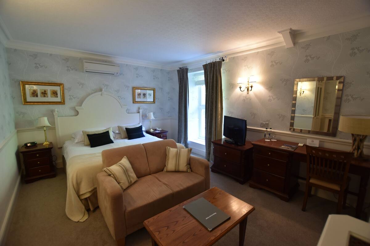 Ein Hotelzimmer mit Bett, Sofa, Schreibtisch und Fernseher.