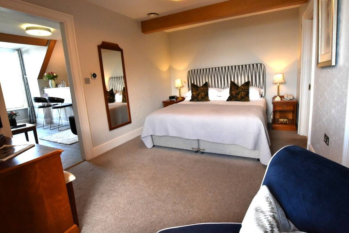 Ein Schlafzimmer mit einem großen Bett, Nachttischen, einem Spiegel und einem Schreibtisch.