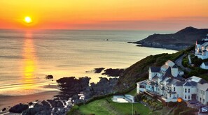 A coastal hotel with multiple buildings, a beach, and rocky terrain. - Watersmeet Hotel (Woolacombe)