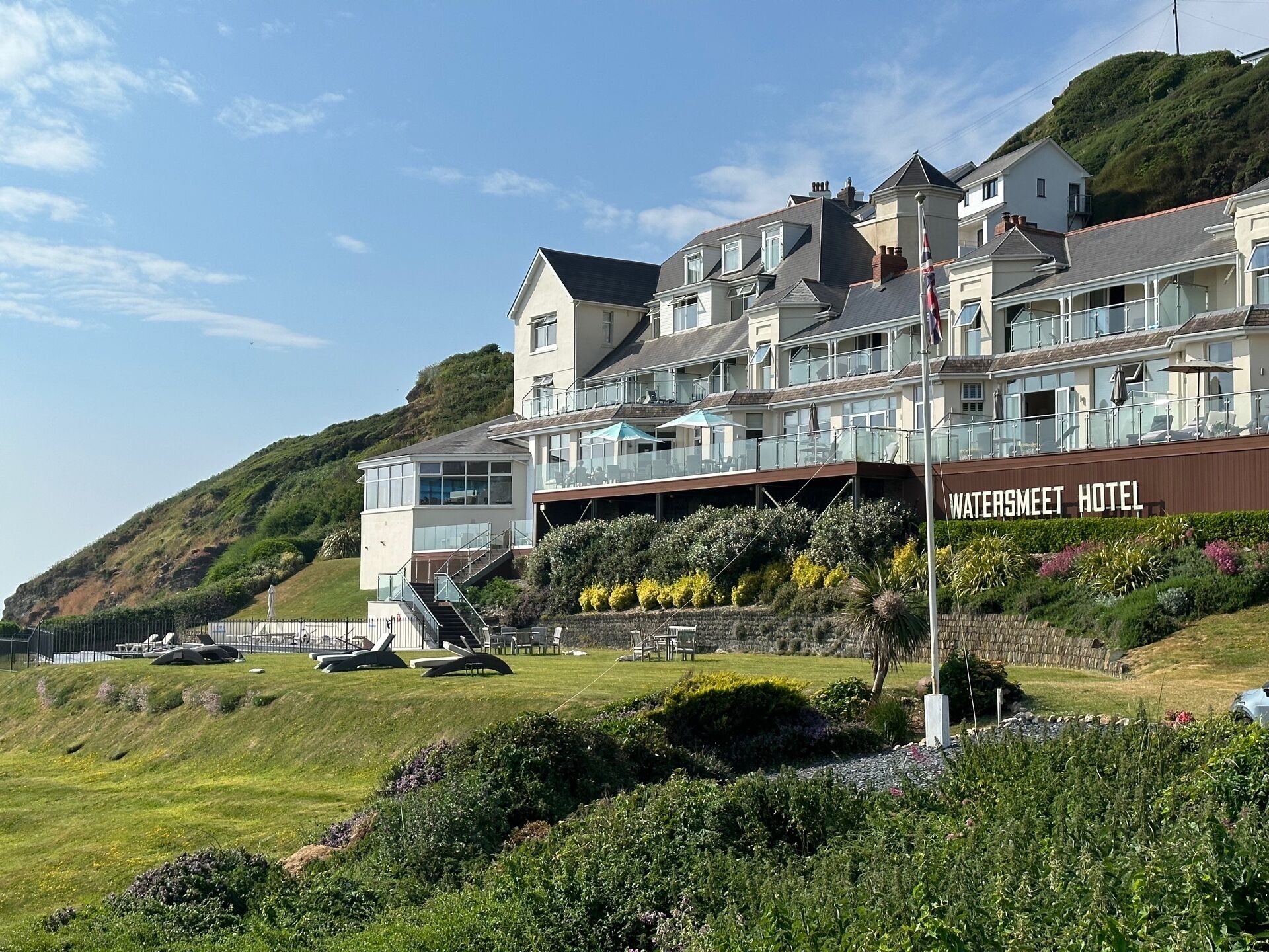 A hotel with multiple buildings, a prominent sign reading "WATERSMEET HOTEL", and a hillside backdrop.