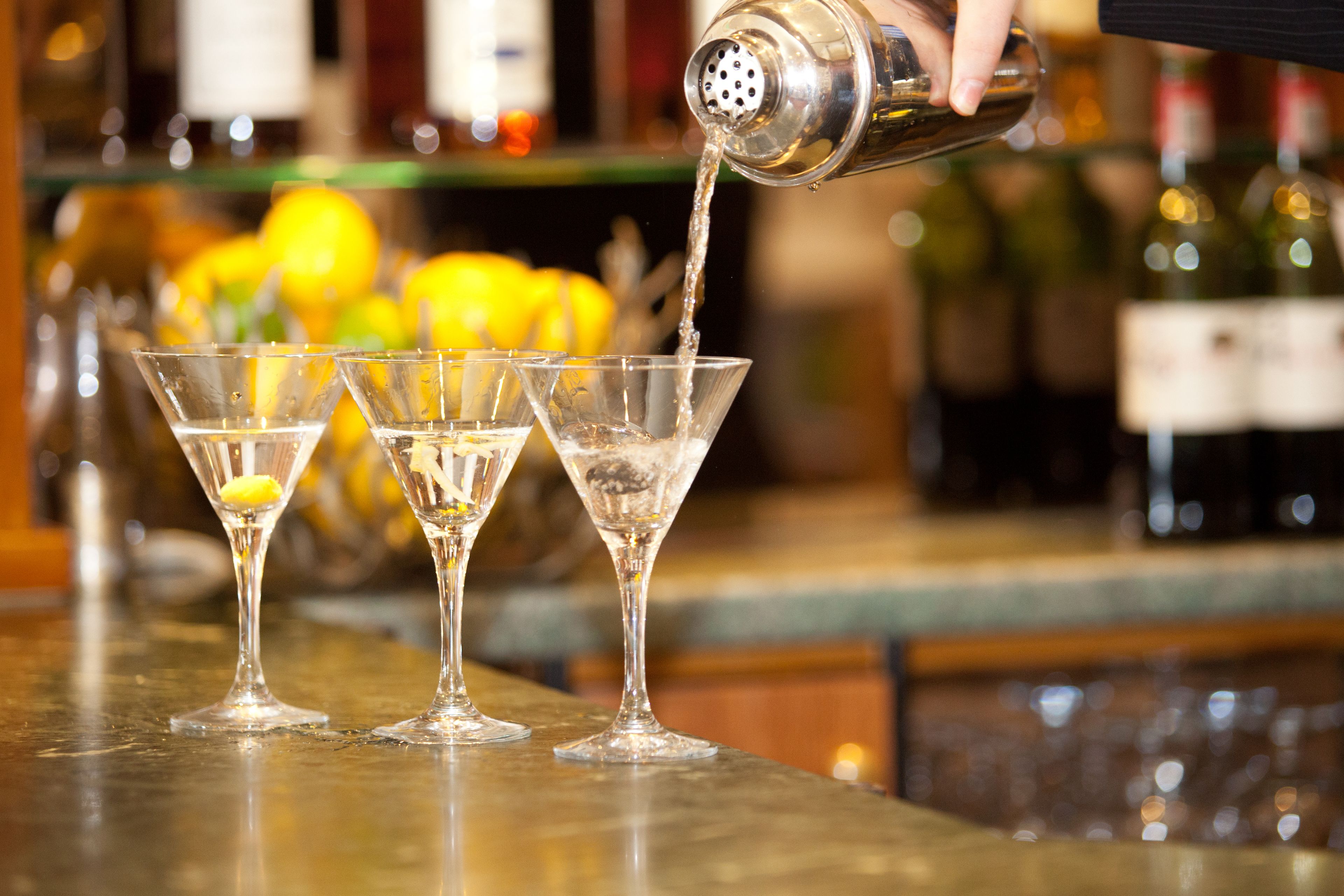 A bartender pouring a drink into a martini glass.