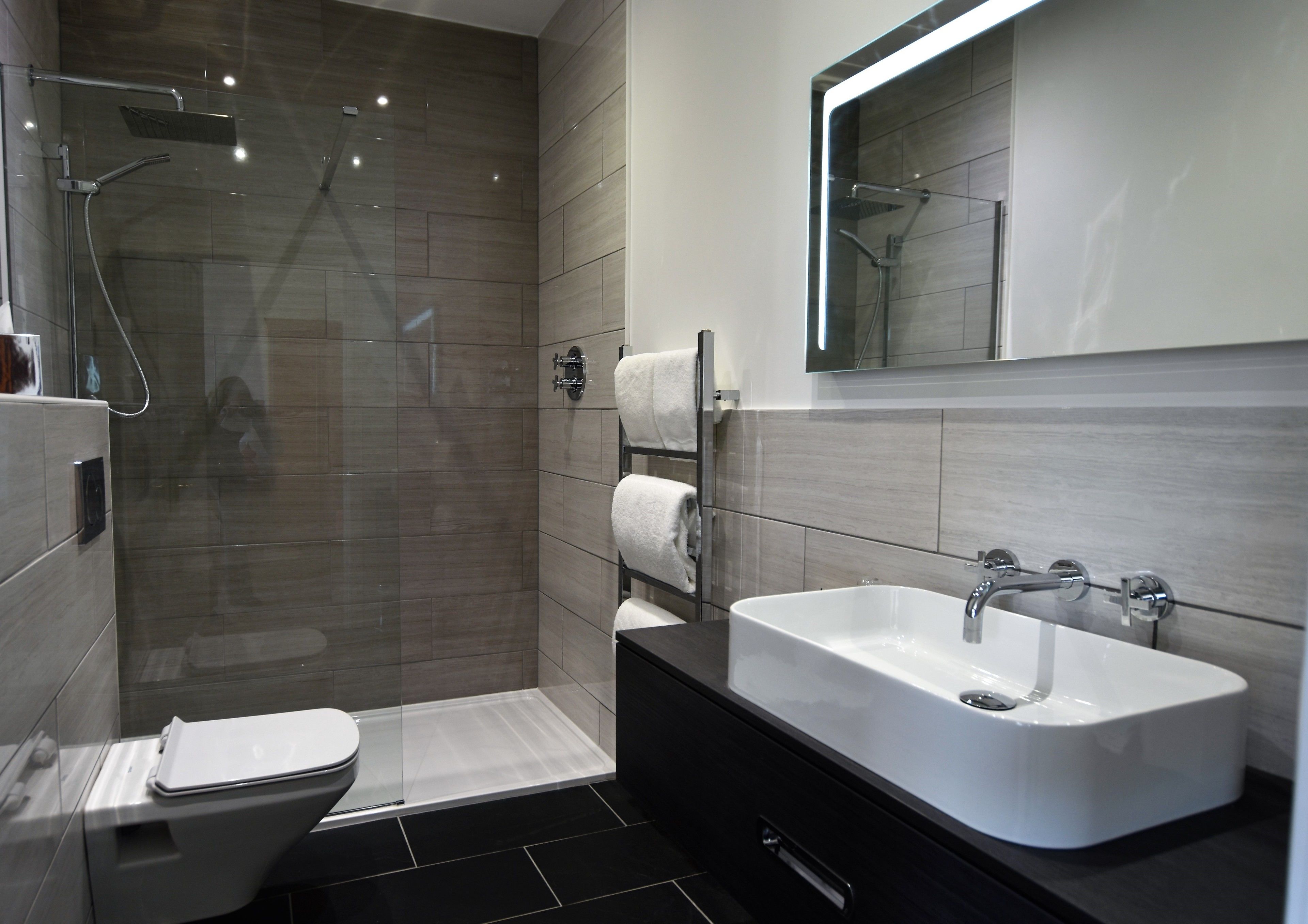 A modern bathroom with a glass-enclosed shower, a white sink, and a toilet.