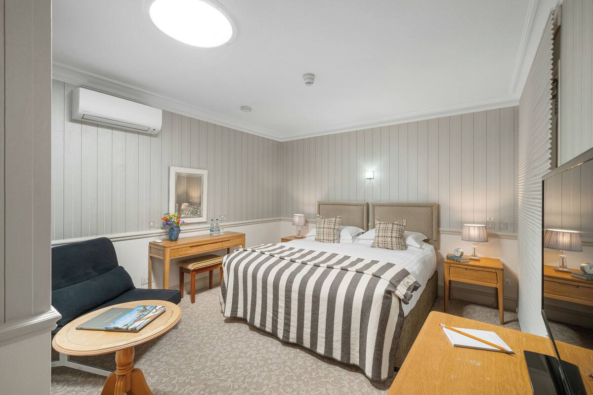 Ein Hotelzimmer mit Bett, Schreibtisch, Stuhl, kleinem Tisch und einer Couch.