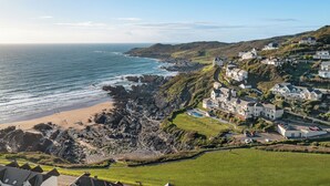 Una zona residencial costera con casas en una colina, una playa y un litoral rocoso.